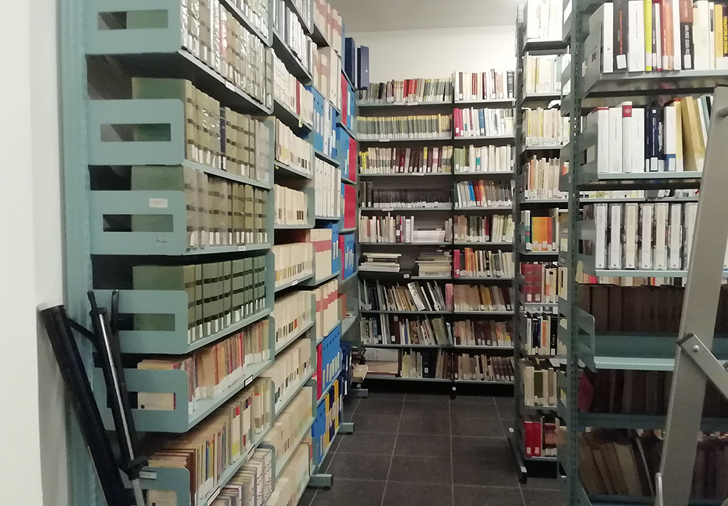 numerosi scaffali pieni di libri creano corridoi in un'ampia sala