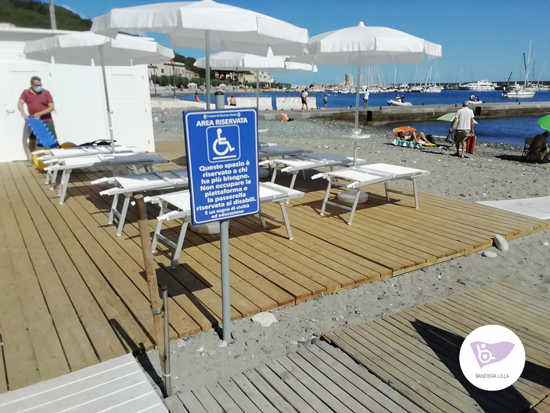 Un esempio di spiaggia accessibile per persone con ridotta mobilità, con una pedana di legno, lettini dedicati e una sedia JOB