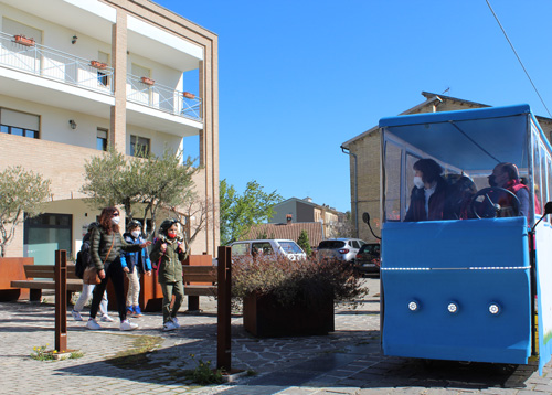 cyclebus davanti alle abitazioni. Dei bambini con lo zainetto sono pronti a salire sul mezzo