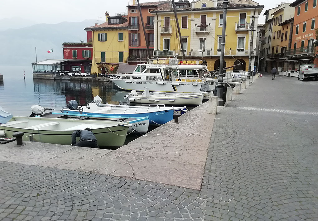 una strada del borgo. Da un lato, piccole imbarcazioni a remi sono attraccate al borgo. Sullo sfondo la via prosegue tra le tante case colorate.