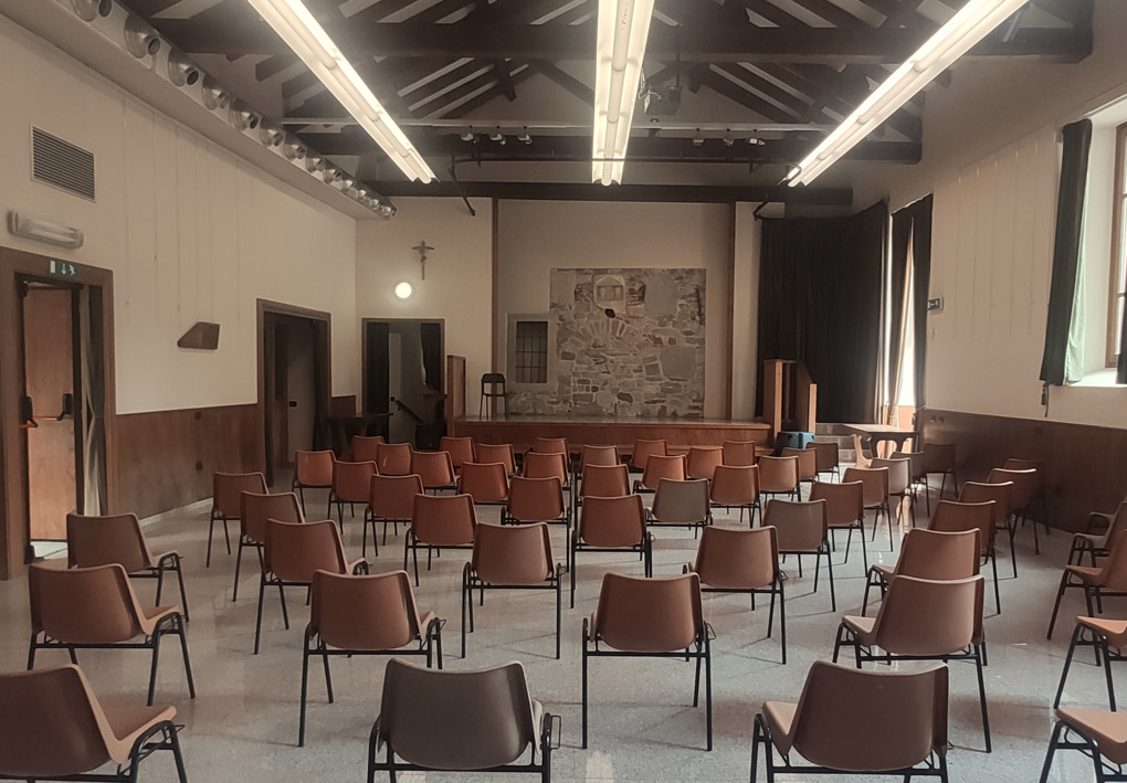una sala con un palco e sedie distribuite