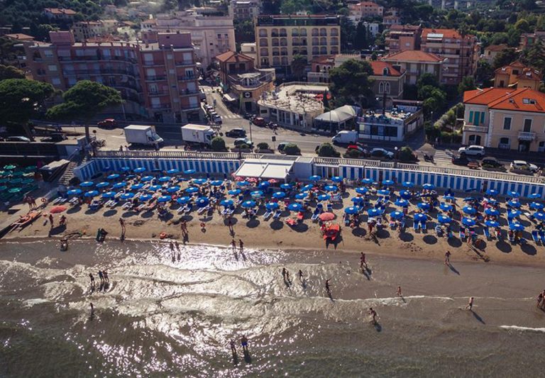 uno stabilimento con varie file di ombrelloni e spiaggia di sabbia