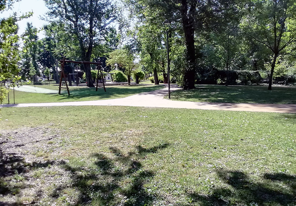 Un parco con molti alberi e terreno erboso. I viali in terra battuta segnano vari percorsi.