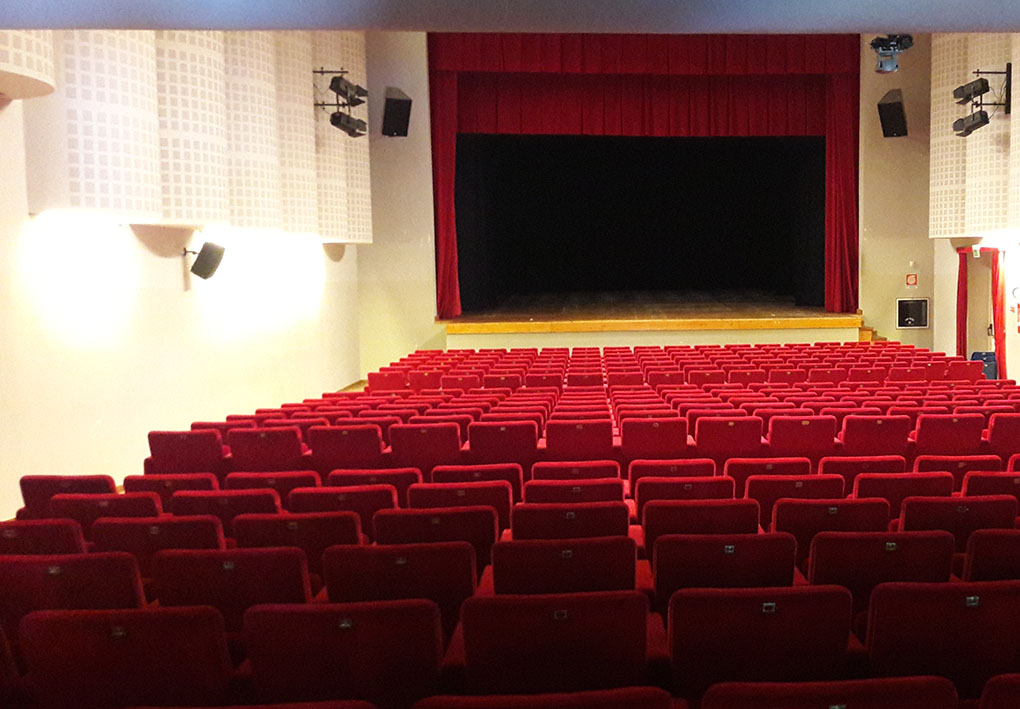 un moderno teatro con file di sedie in velluto in platea