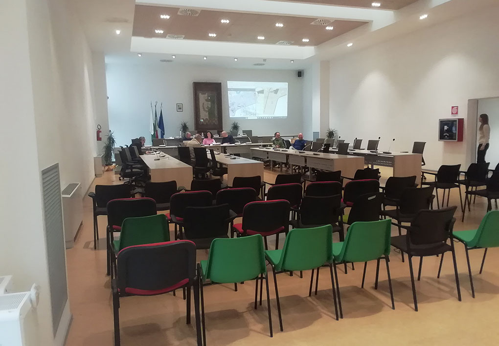 una moderna sala di un consiglio comunale, con i tavoli da conferenza e sedie di plastica a formare la platea