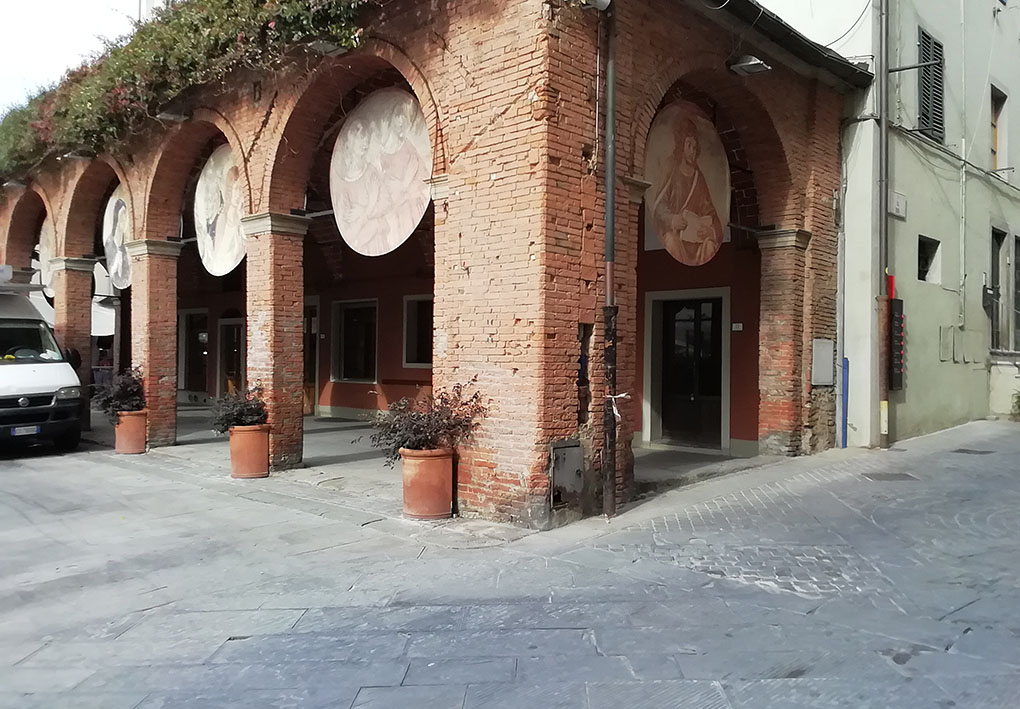 riproduzioni di dipinti sono appese negli archi del porticato di un edificio in mattoni