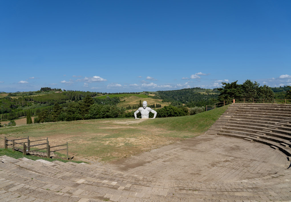 La cavea dell'anfiteatro ricavato nella collina. Una statua gigante di un uomo si erge dal terreno