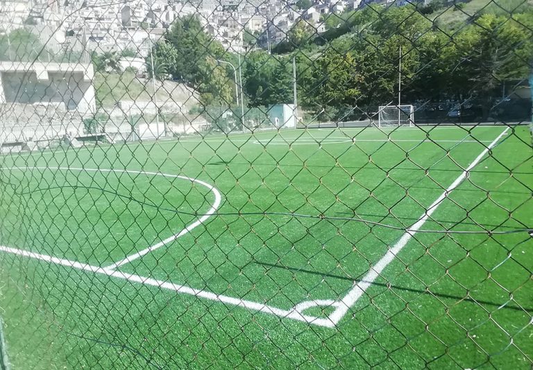 campo da calcio circondato da una rete e alberi