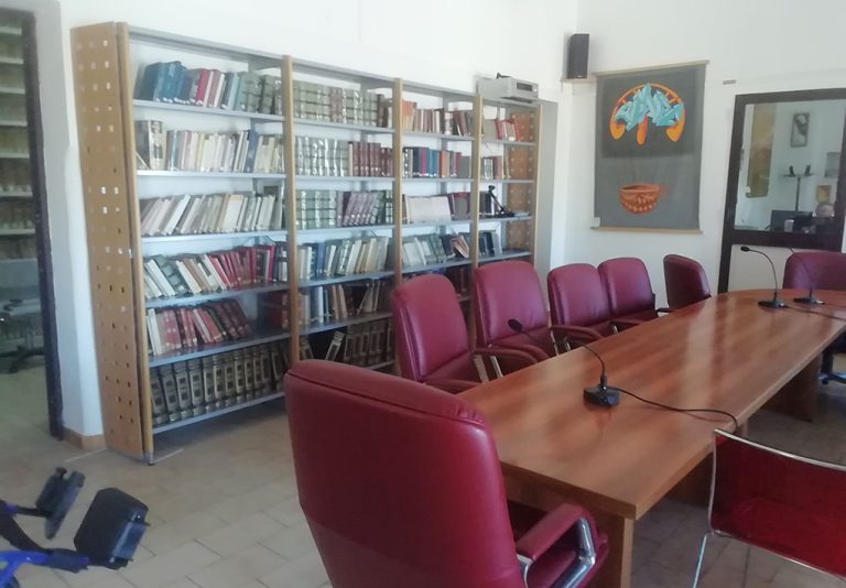 un tavolo da riunione in una sala con scaffali di libri alle pareti