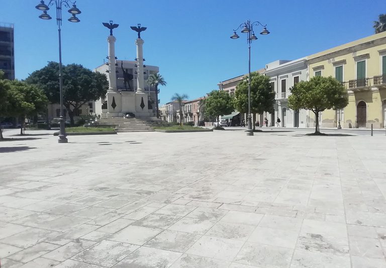 un'ampia piazza pianeggiante con alberi e un monumento al centro