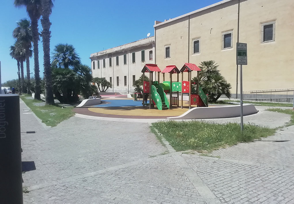 in un ampio piazzale, un'area giochi tra le aiuole