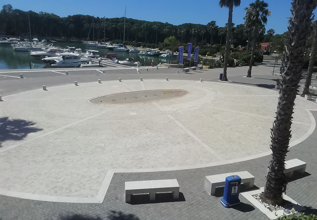 un'ampia piazza in riva al mare, con palme e panchine