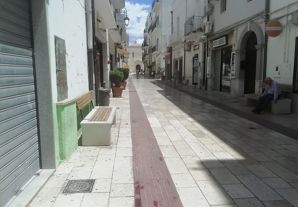 Una strada con panchine e un percorso podotattile