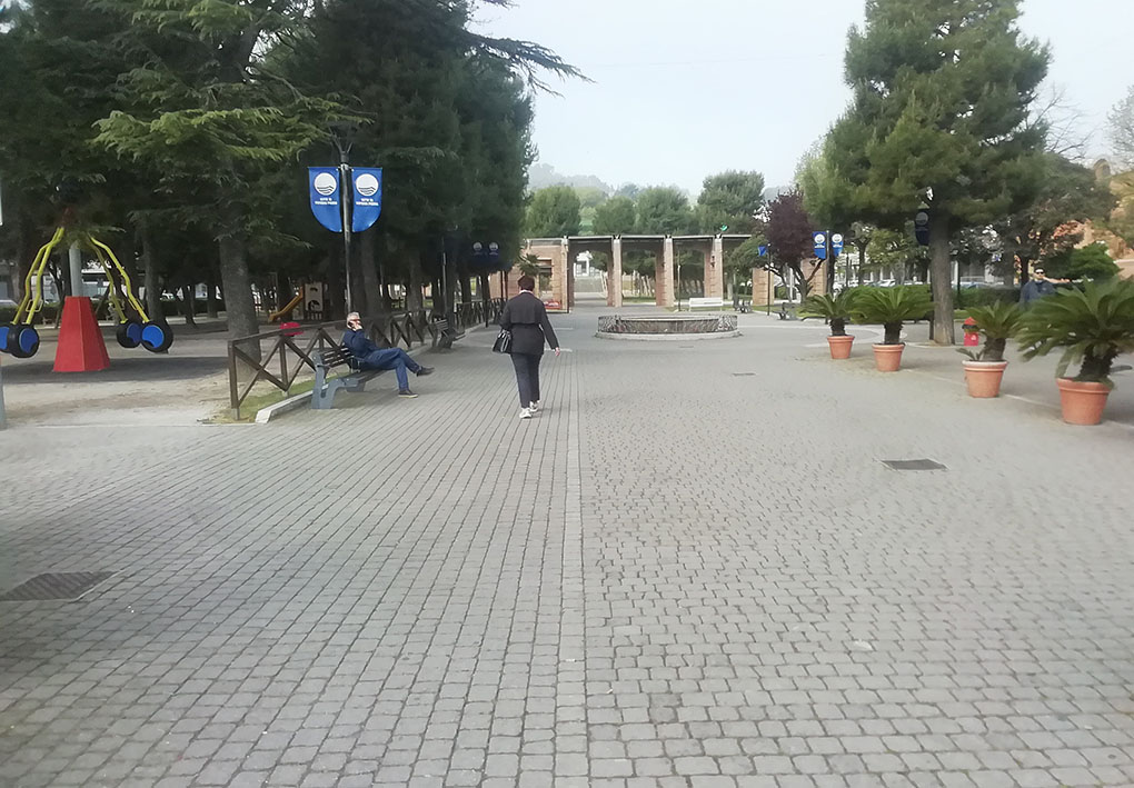 un'ampia piazza pedonale con panchine, alberi e giochi per bambini