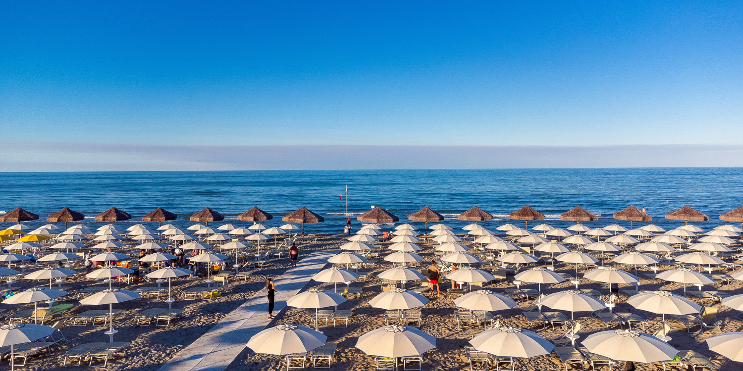 spiaggia sabbiosa con numerose file di ombrelloni in una giornata limpida