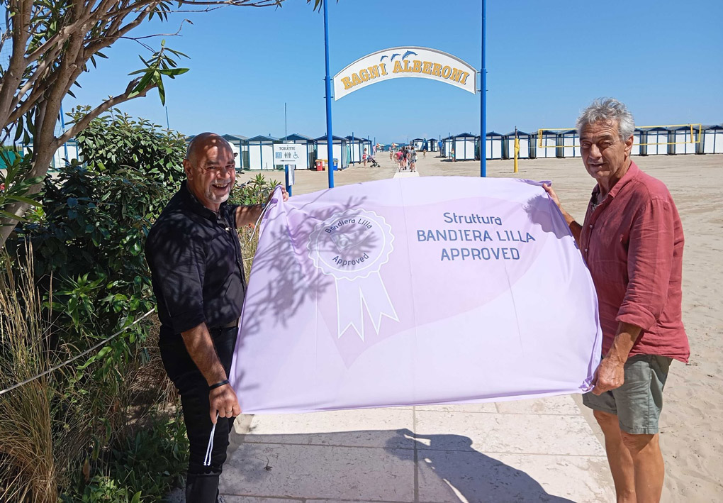 Il gestore dei Bagni Alberoni e il presidente della Bandiera Lilla esibiscono il riconoscimento Bandiera Lilla Approved