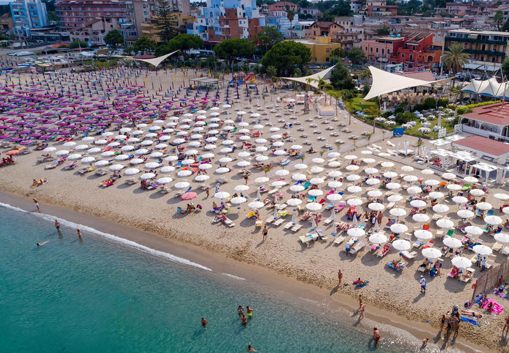 La spiaggia sabbiosa con numerose file ordinate di ombrelloni
