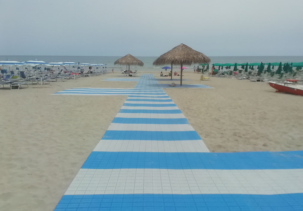 una spiaggia libera in sabbia con passerella, piazzole e zone in ombra