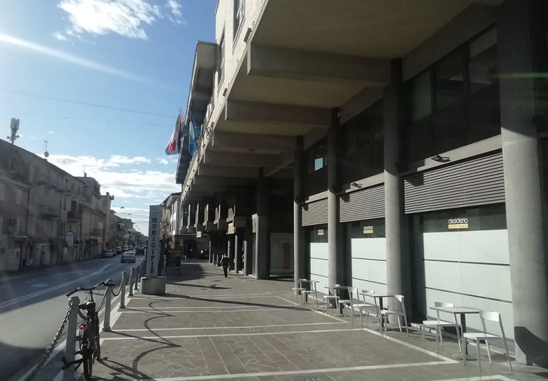 Sun un ampio marciapiede coperto da una tettoia, un'installazione segnala l'entrata del municipio