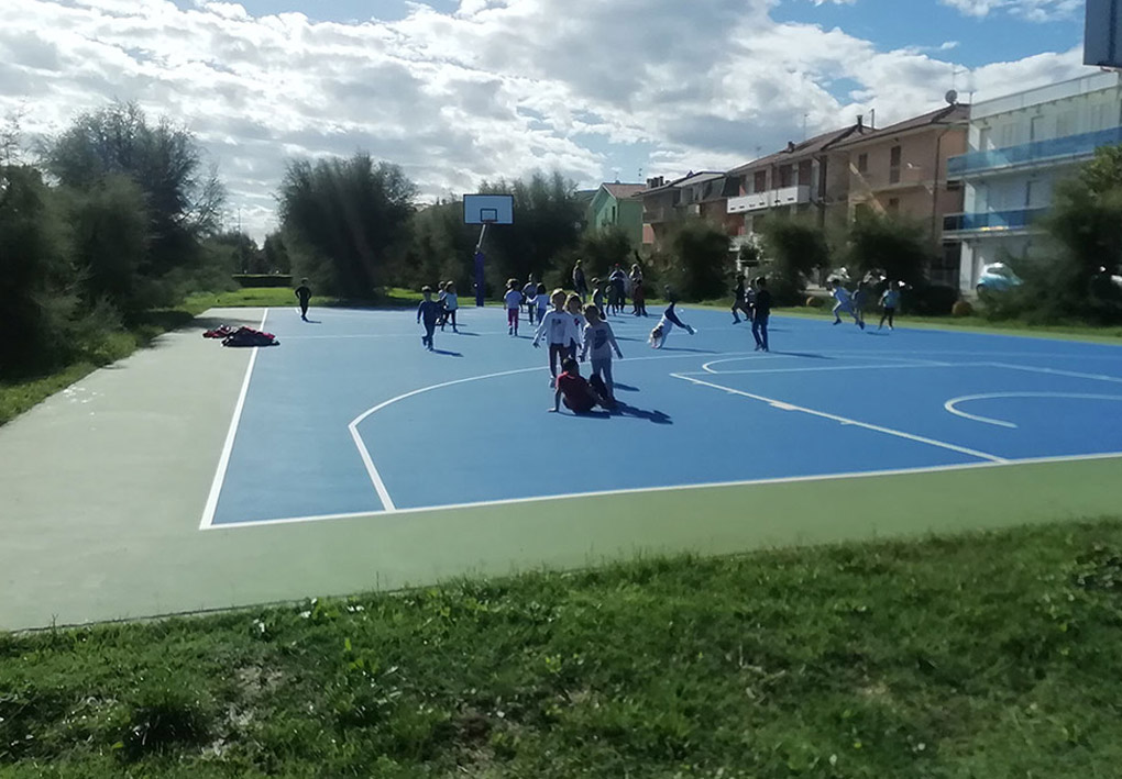 bambini giocano in un campo da basket tra le case