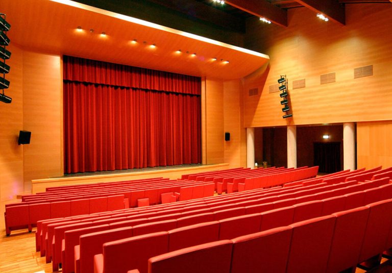 L'interno di un moderno teatro, con pareti in legno e file di sedie in una platea inclinata