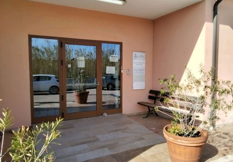 un ampio ingresso con una zona antistante la porta, coperta e provvista di panchina. Due vasi di piante la decorano