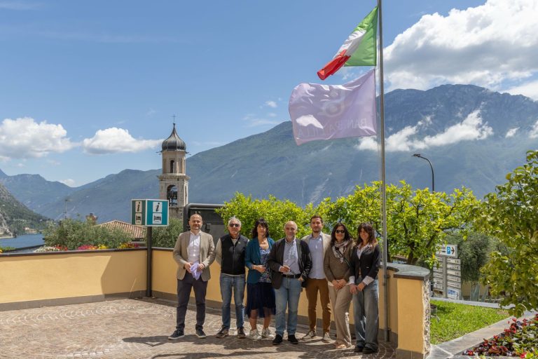 Il presidente di Bandiera Lilla posa con il Sindaco e gli Assessori di Limone sul Garda, su una terrazza della città. Sopra di loro, su un pennone, sventolano la Bandiera italiana e la Bandiera Lilla