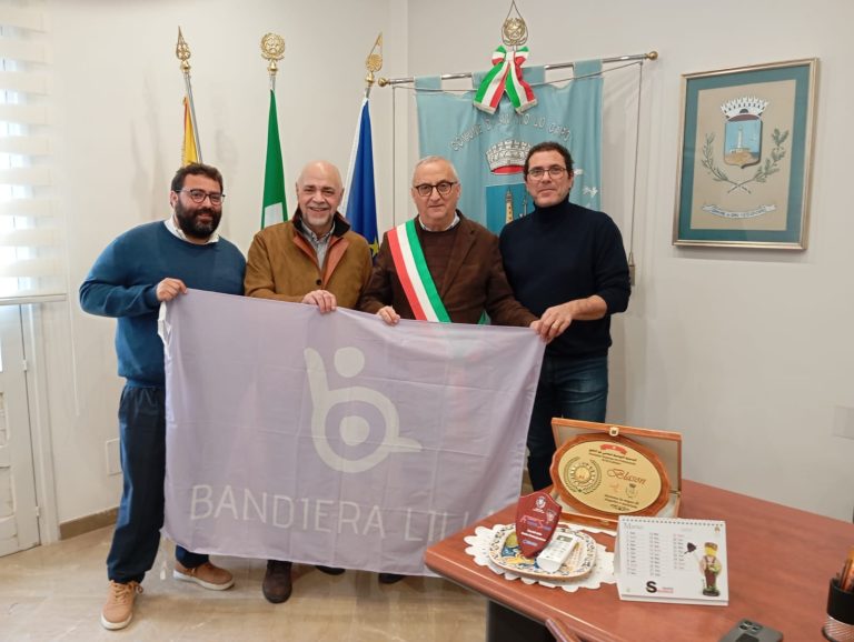 Il presidente di Bandiera Lilla, Roberto Bazzano, posa con la bandiera, gli assessori e il Sindaco di San Vito lo Capo