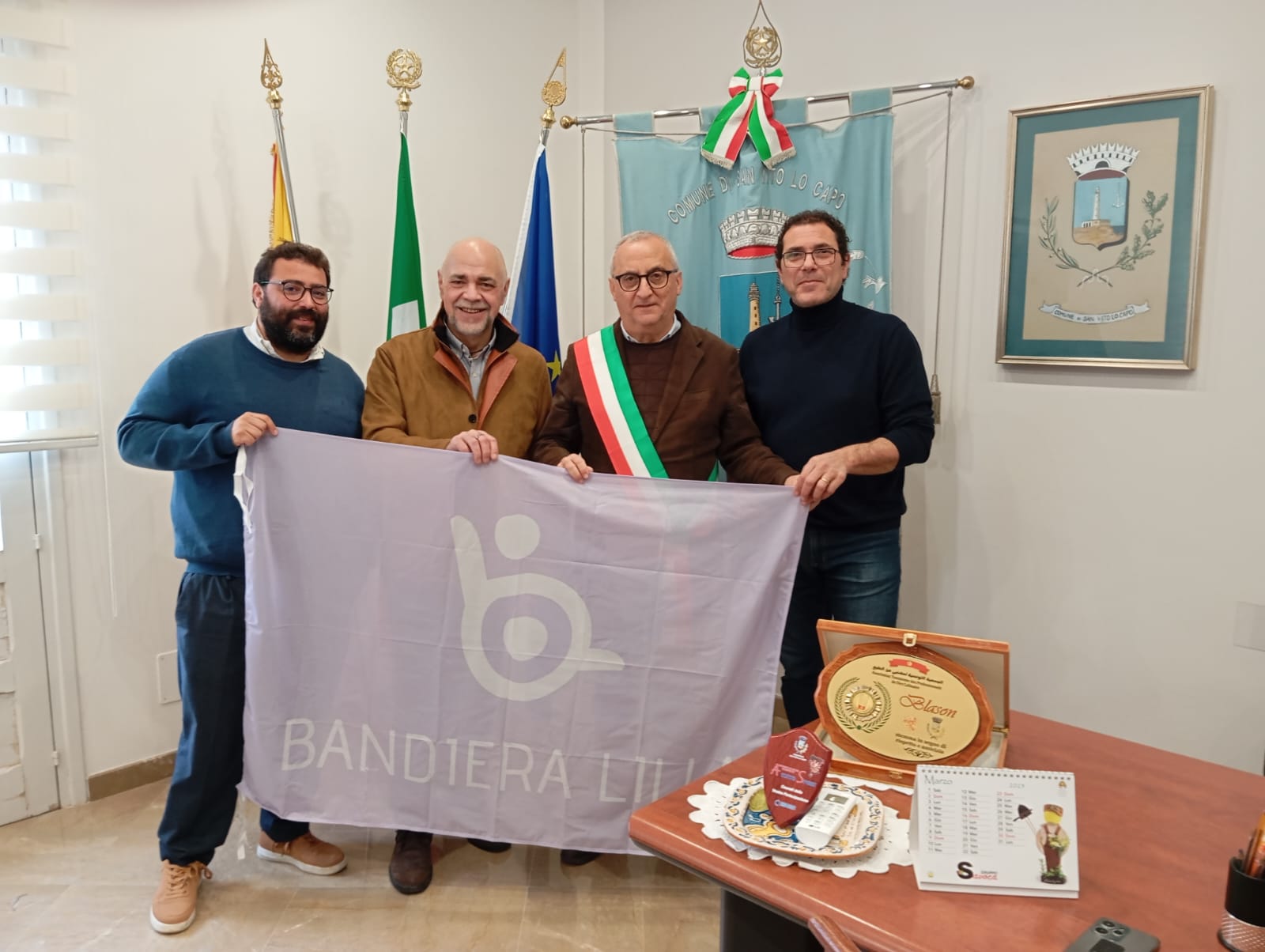 Il presidente di Bandiera Lilla, Roberto Bazzano, posa con la bandiera, gli assessori e il Sindaco di San Vito lo Capo