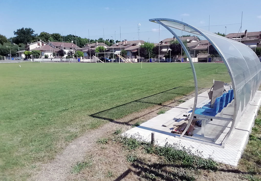 un campo da calcio con la panchina lungo i bordi riparata da una struttura in plastica