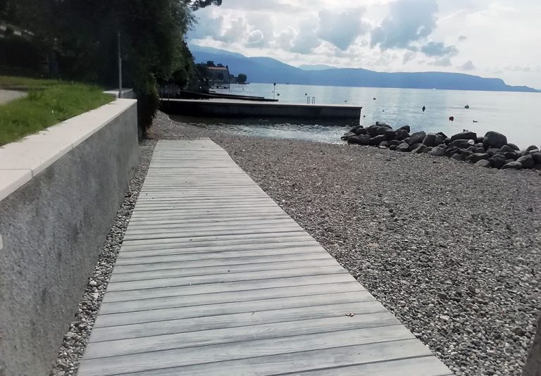 Spiaggia con in primo piano una rampa di acceso. Sullo sfondo il paesaggio del lago