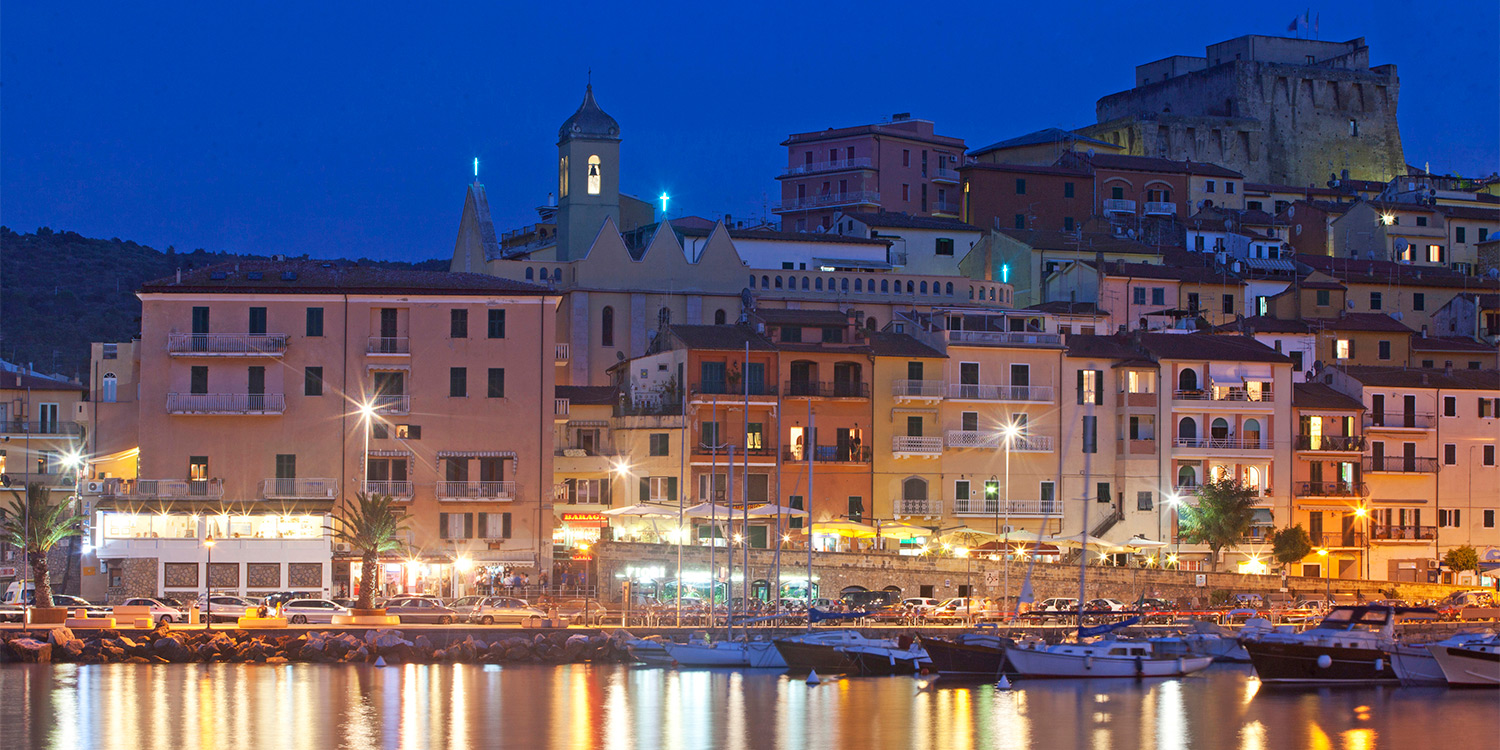 di sera, le luci del borgo marinaro si specchiano nel mare