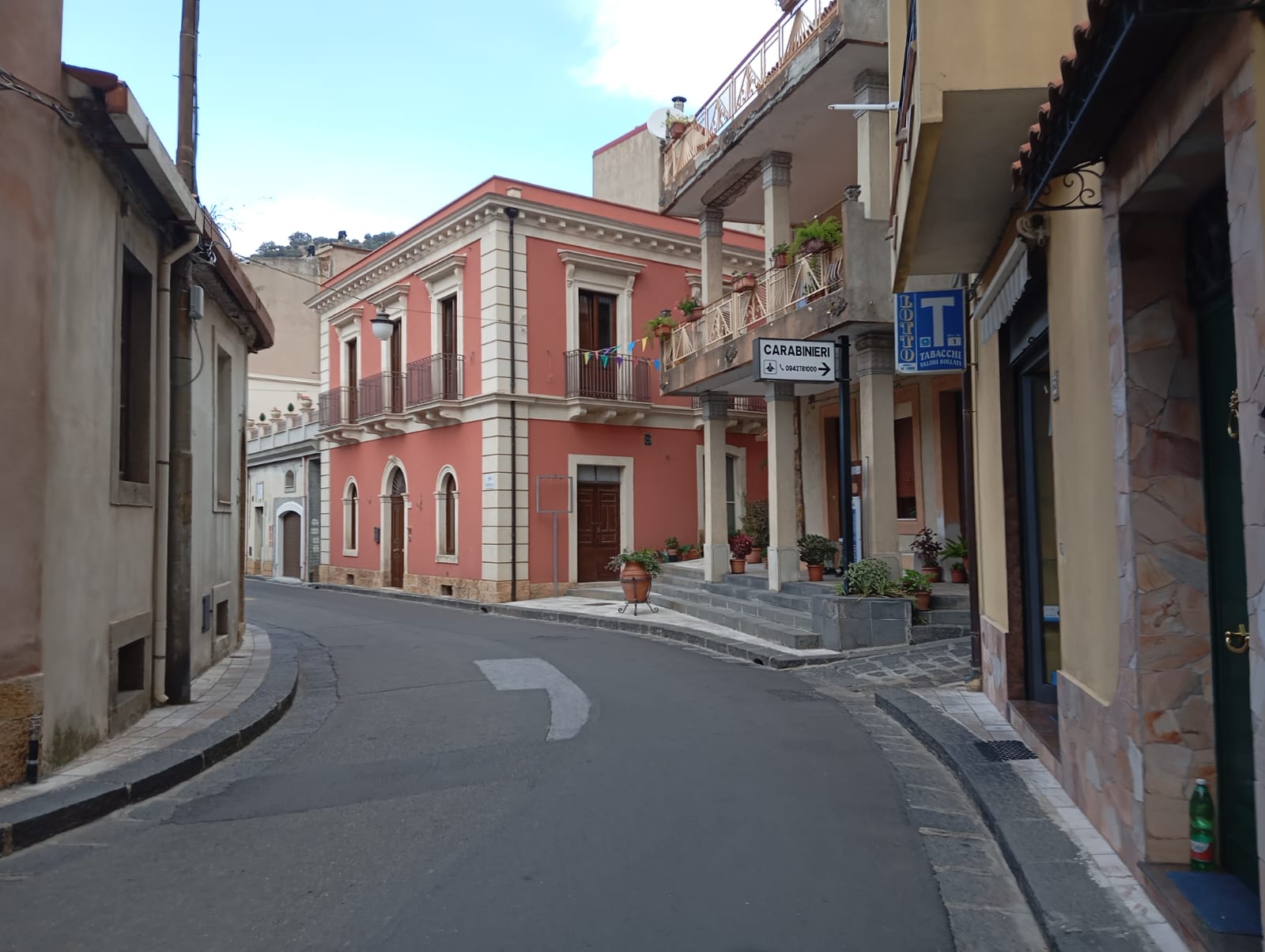 Stradina tranquilla in borgo mediterraneo con edifici colorati, con finestre ad arco, segnaletica di vario genere.