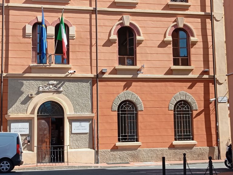Palazzo in mattoni rossi con bandiere all'ingresso.
