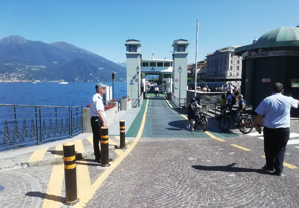 una lunga rampa permette l'accesso dei veicoli ai traghetti. Sullo sfondo colline e il lago in una giornata di sole
