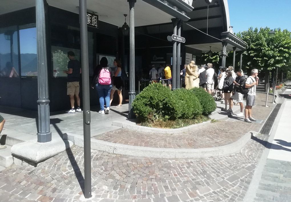 una lunga e dolce rampa permette l'accesso a una pensilina dove è posizionata la biglietteria. Molte persone in fila affollano la scena