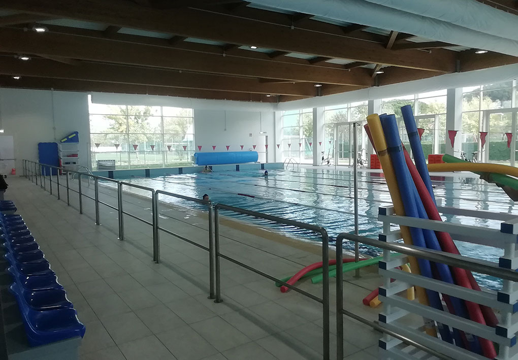 una piscina coperta, con ampie finestre per fare entrare la luce. A lato seggiolini per gli spettatori.
