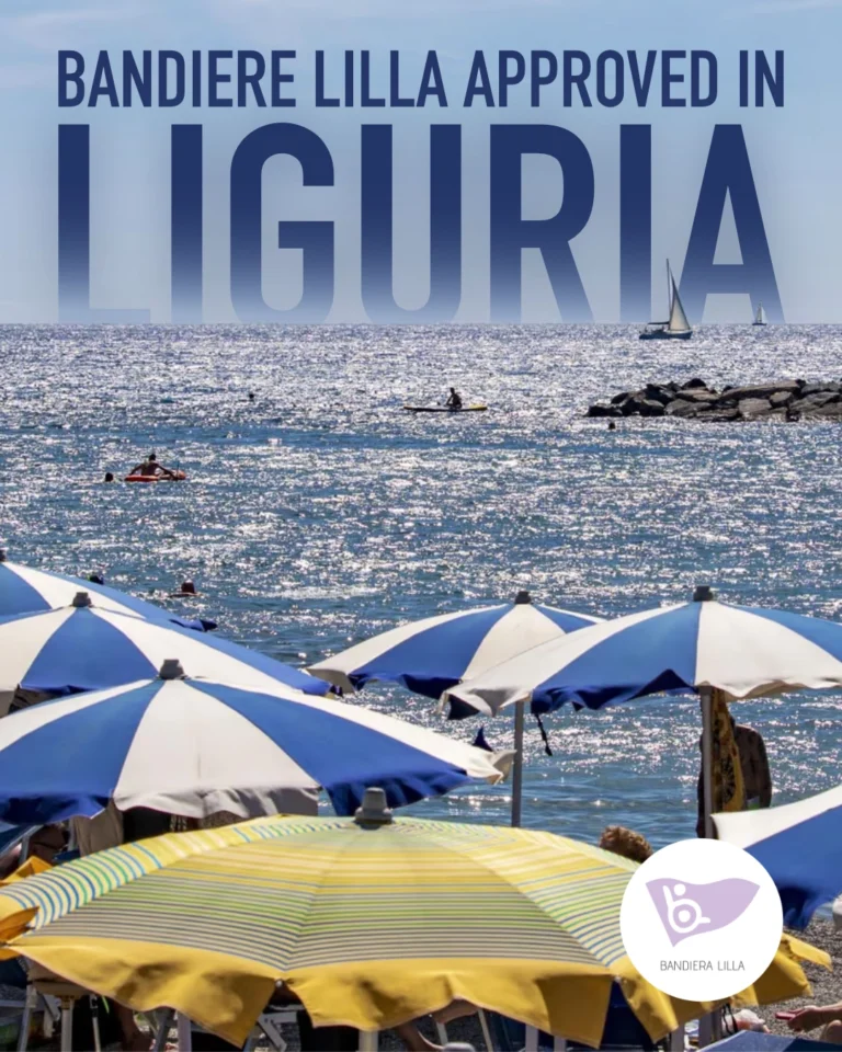 Foto della spiaggia in una giornata di sole. In alto c'è la frase in blu: "BANDIERE LILLA APPROVED IN LIGURIA". In primo piano ci sono diversi ombrelloni da spiaggia aperti, gialli con strisce verdi e blu scuro e bianchi. Dietro gli ombrelloni, c'è il mare con dei bagnanti e una barca a vela. Nell'angolo in basso a destra c'è il logo di Bandiera Lilla.