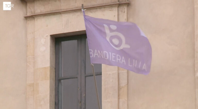 la bandiera lilla sventola sulla facciata di un municipio. Il logo TgR in alto segnala che l'immagine è estrapolata da un servizio del telegiornale