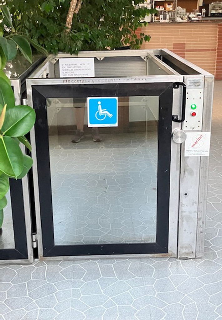 Piattaforma elevatrice con struttura in metallo e sportello a vetro, dotata di pulsantiera